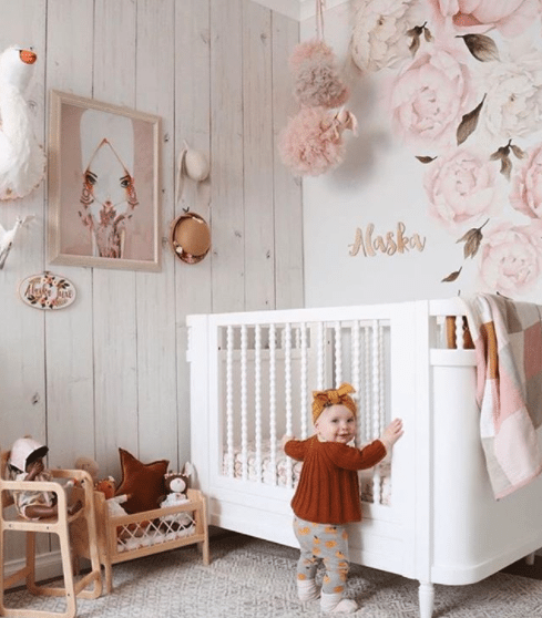 nursery using Whitewashed Timber wallpaper, the best seller for 2017, with white crib. wood carved name Alaska and baby girl standing