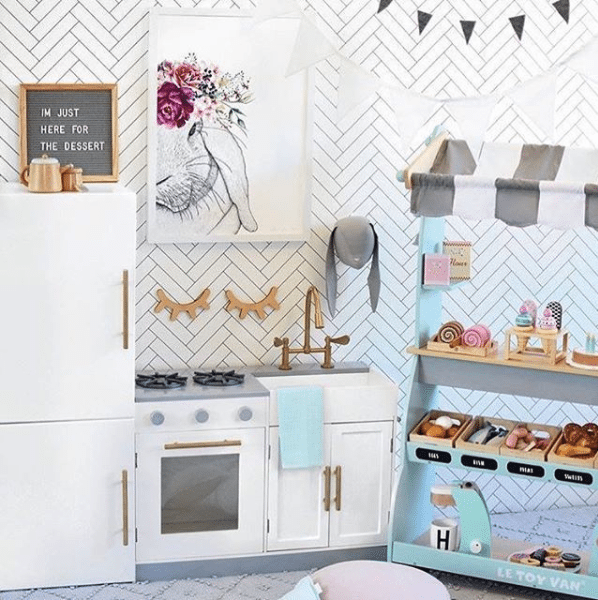 Kids playroom with Kmart kitchen set and white Tile Progress Wallpaper from Milton & King on the wall 