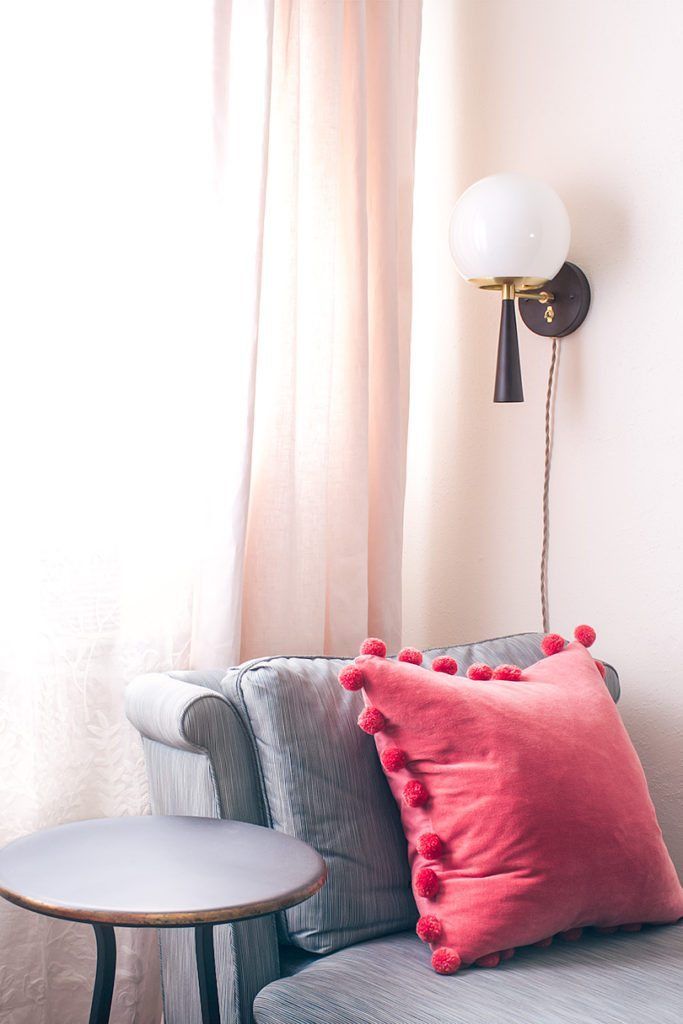 gray vintage slip chairs with salmon colored pillow and wall sconce