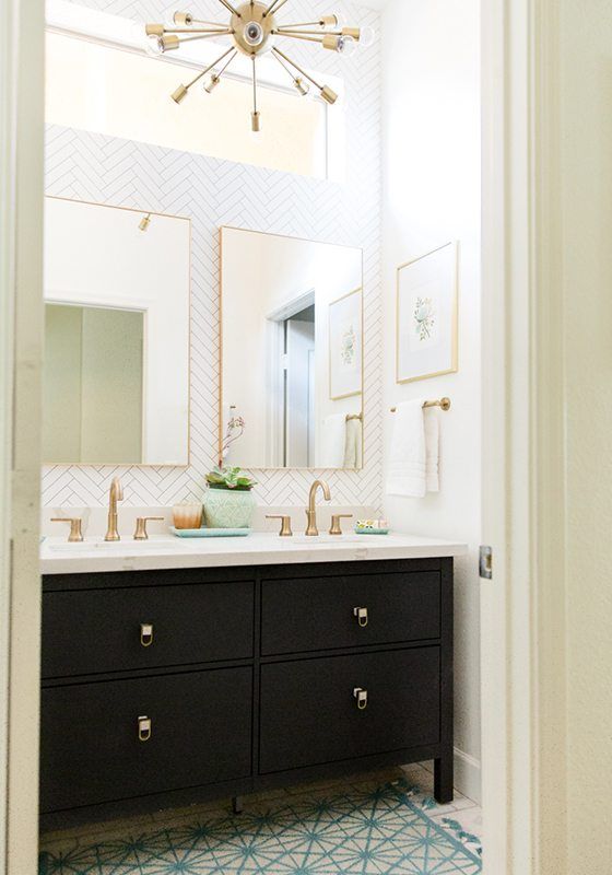 photo of a bathroom with dark cabinets, a his and hers sink with brass faucets and handles and a herringbone wallpaper called Tile Progress from Milton & King