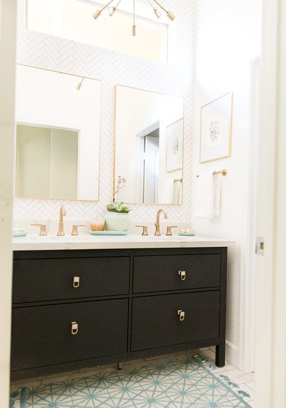 Wide shot showing the guest bathroom remodel with brass sink accents, white painted walls and dark painted vanity.