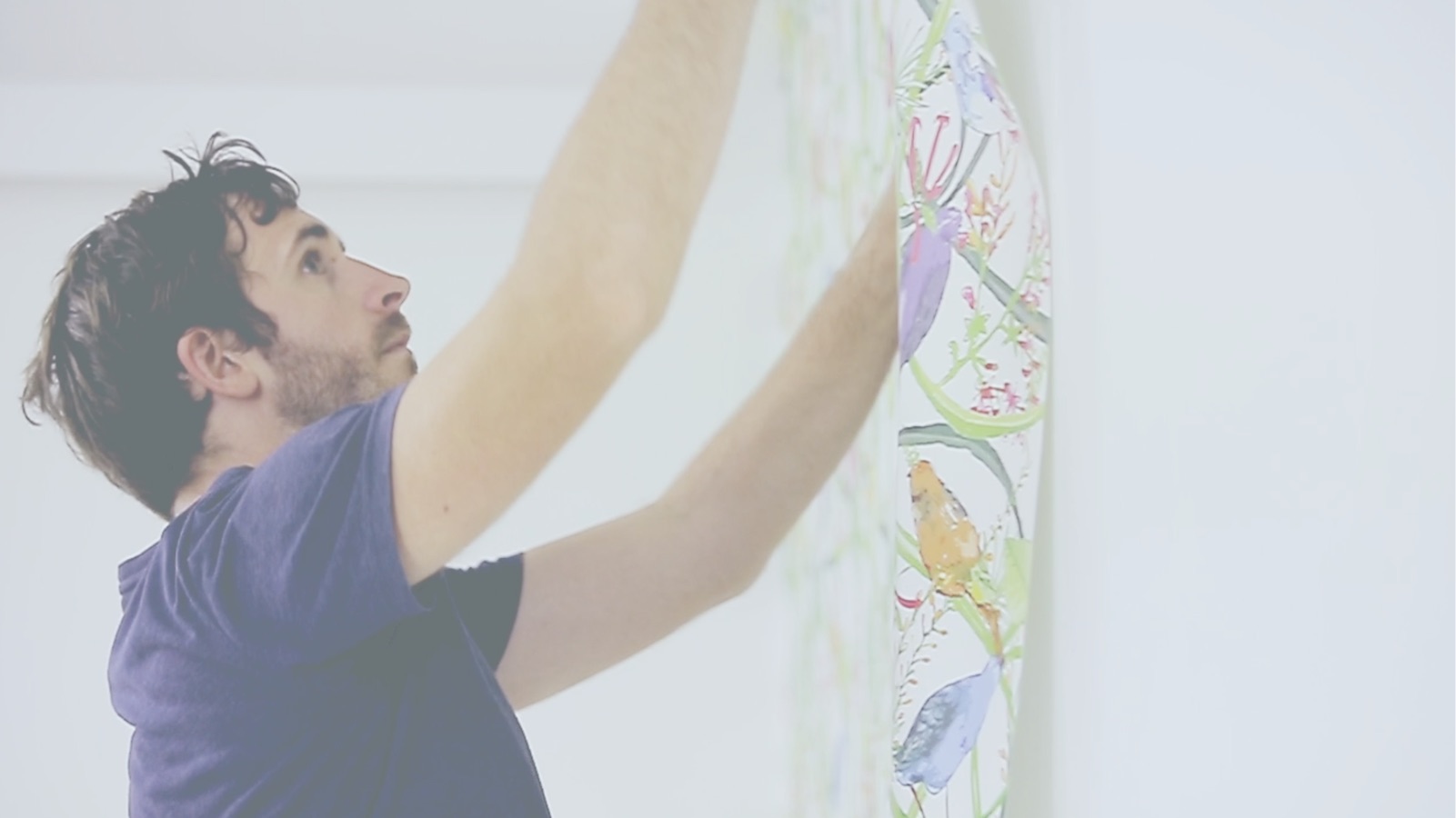 A man hanging wallpaper on a clean white wall