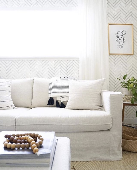 Tile Progress Wallpaper, neutral wallpaper featuring a herringbone pattern behind a white sofa. Living Room Wallpaper