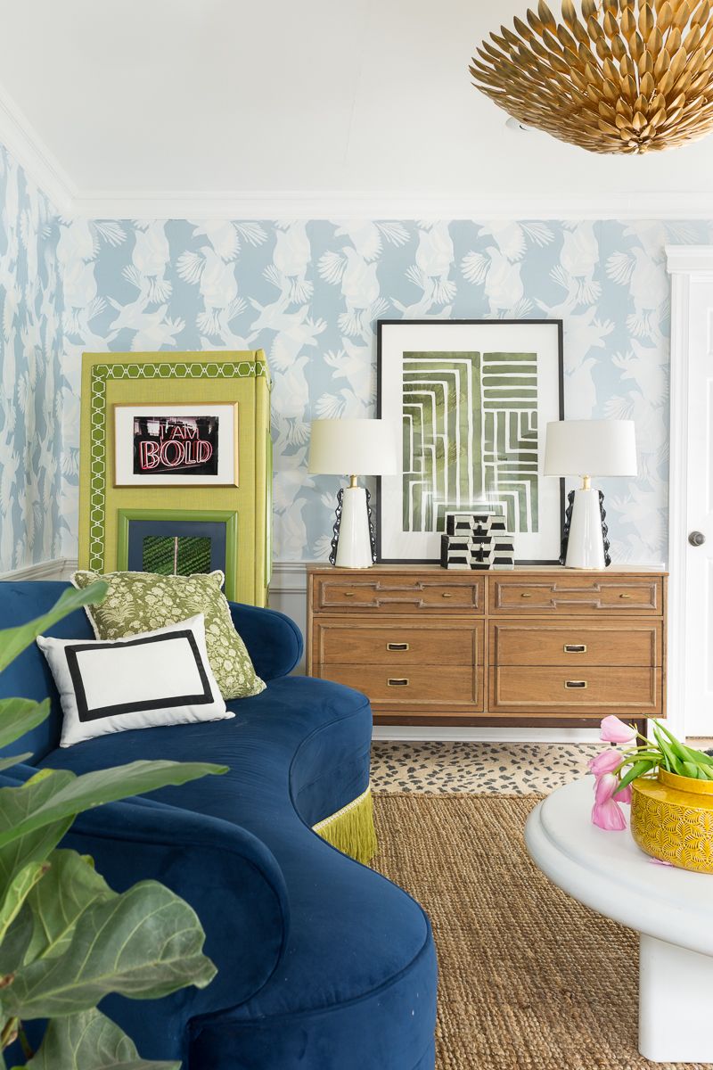 Jewel Marlow Basement Makeover • a dark blue sofa with lime green fringe sits in front of a lime green room divider. There is light blue Magpie Wallpaper from Milton & King on the back wall