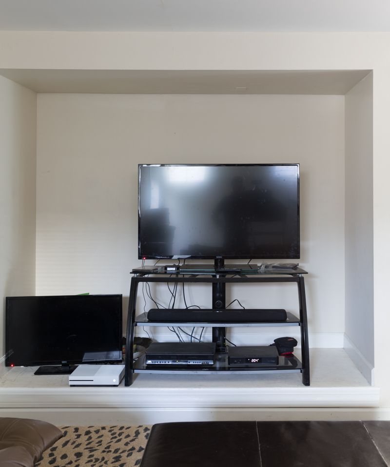 Jewel Marlow Basement Makeover • A TV sits on a black minimal stand against a white wall