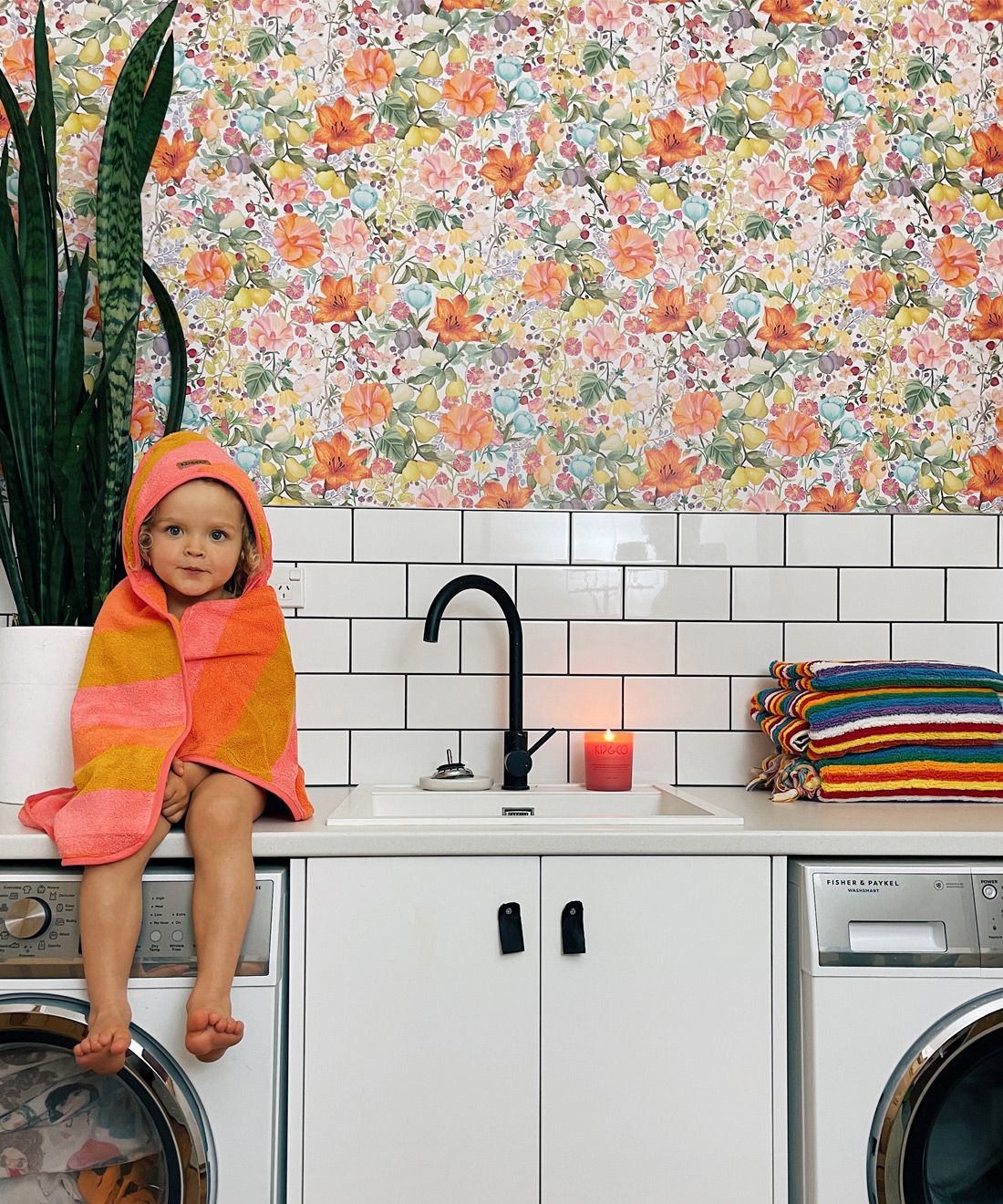 Abundance Wallpaper • Kip&Co • Colorful Floral Wallpaper • laundry room insitu with young girl sitting on washing machine by Rosie Clark