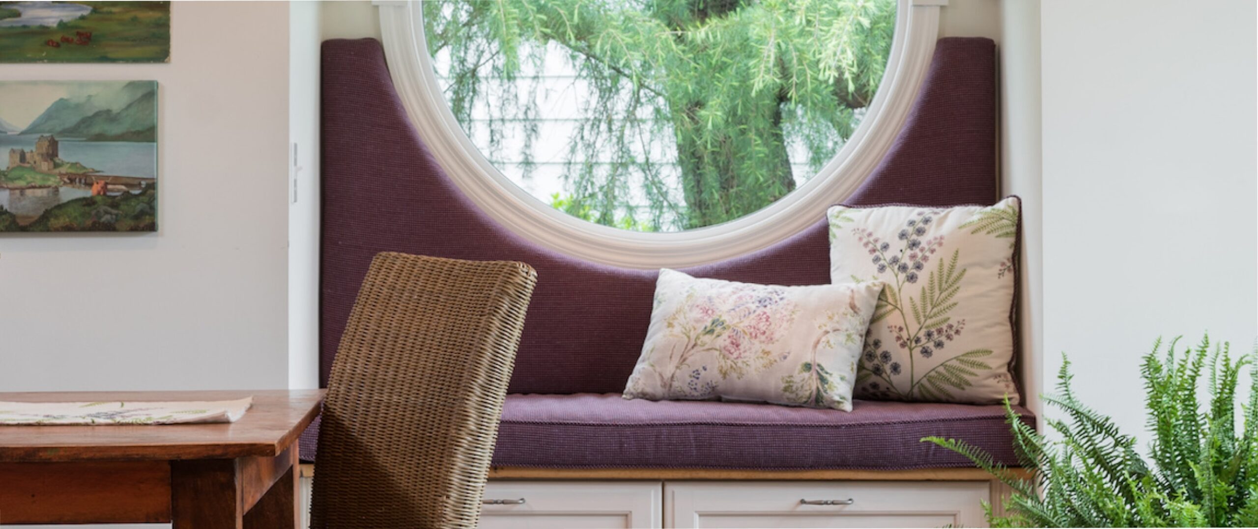 a dining room with a round window and purple cushions