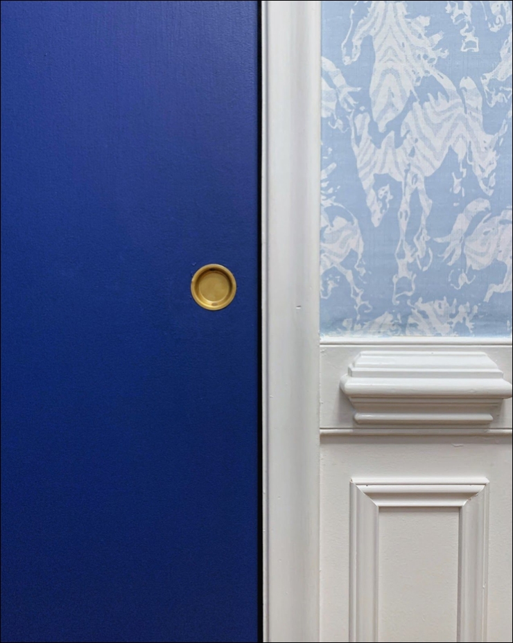 Close up image of newly painted blue door and the Stampede wallpaper from Milton & king above the wainscoting