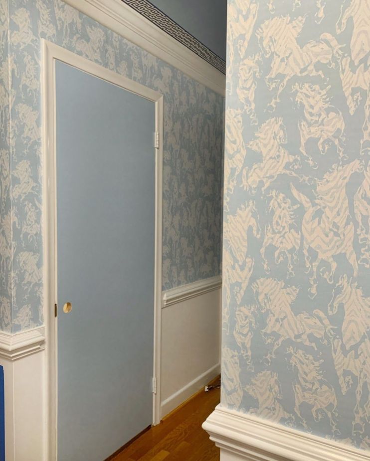 Hallway with Stampede Wallpaper by Milton & King. The wallpaper is light blue with horses. The doors are also painted light blue to match the wallpaper.