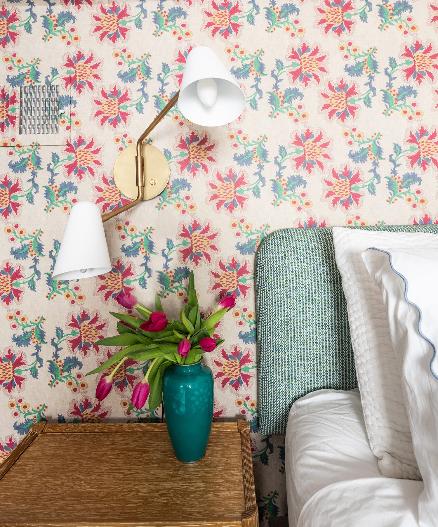 Contemporary Lamp on the side of a bed with white linen. On the night stand is a floral arrangement in an aqua vase