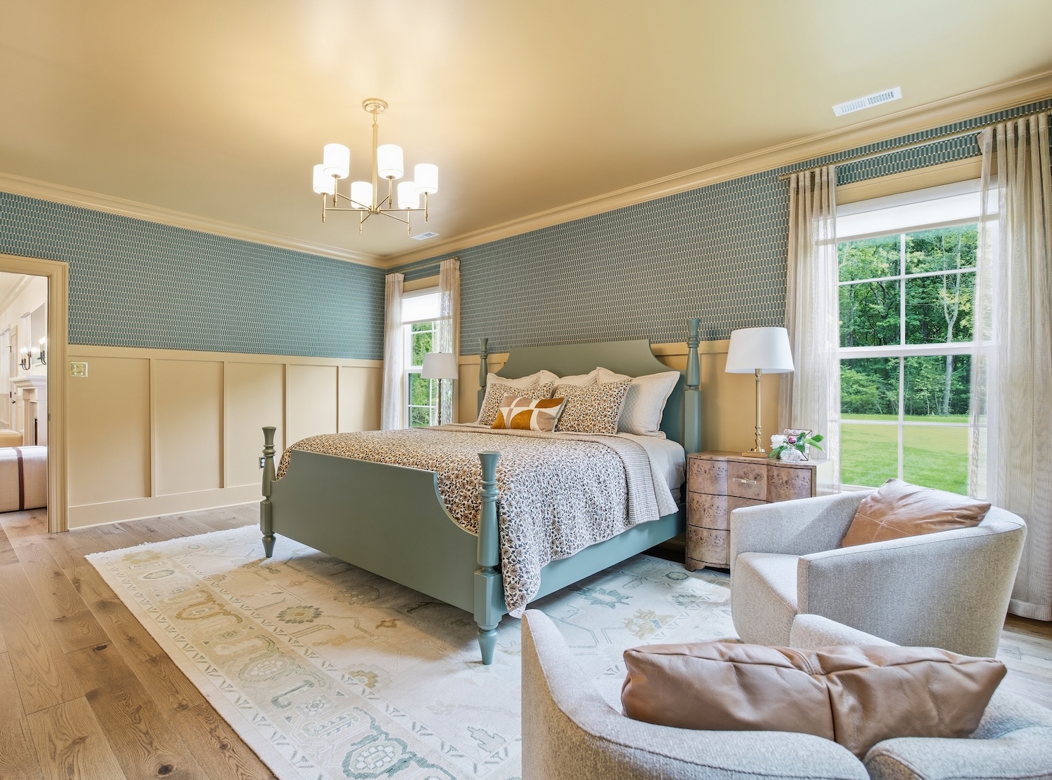 Bedroom with cream colored wainscotting and a geometric wallpaper on the upper portion of the wall