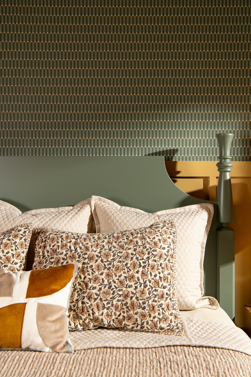 Bedroom with cream colored wainscotting and a geometric wallpaper on the upper portion of the wall