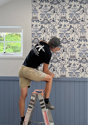 Man standing on a ladder installing wallpaper